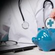 Doctor inserts a coin with a blue medical cross into a blue piggy bank, symbolizing health savings.